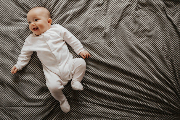 Beautiful cute baby lying and playing on the bed in the room, photo with daylight from the window - Fotoğraf, Görsel