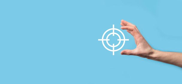 Targeting concept with hand holding target icon dartboard sketch on chalkboard. Objective target and investment goal concept - Photo, Image