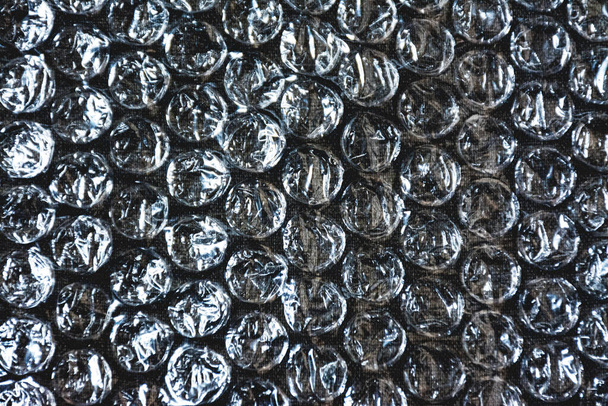 Película de plástico transparente de burbujas sobre un paño oscuro texturizado como fondo de diseños - Foto, Imagen