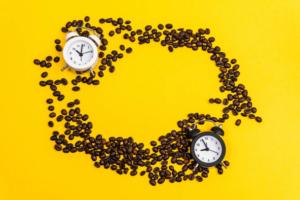Coffee beans, alarm clock, on yellow background. Creative Concept time to work. Flat lay top view copy space - Foto, Bild