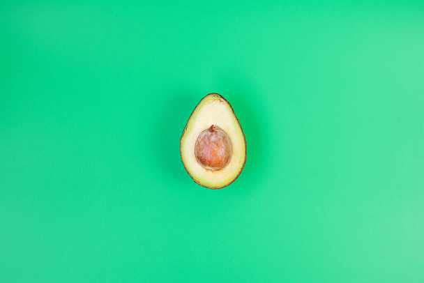 Organic avocado with seed on green background. Superfood, fruit, Healthy food, Keto diet and vegetarian concept - Photo, Image