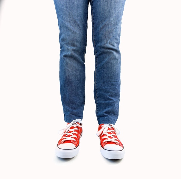 Studio shot of a woman's legs with jeans and red sneakers isolated on white - Φωτογραφία, εικόνα