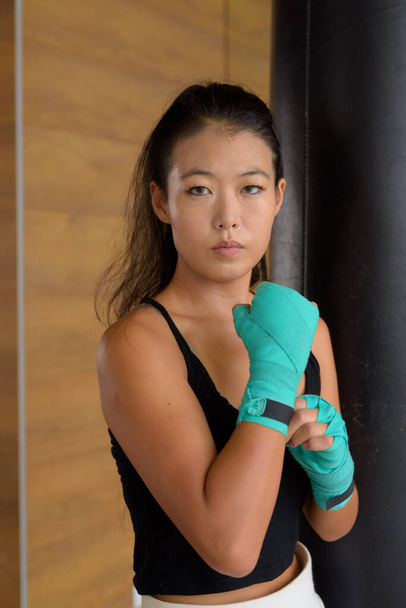Гарна молода азійка копає боксер, готовий до тренувань у спортзалі. - Фото, зображення