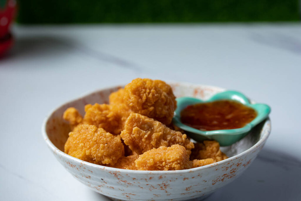 Fried chicken with chicken dipping sauce in a ceramic cup on a white table. - Photo, Image