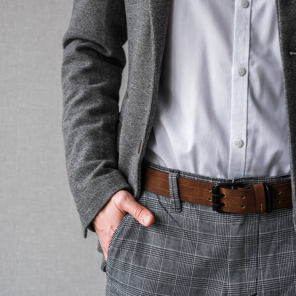 egy férfi klasszikus szürke dzsekiben és fehér ingben, világos háttérrel. üzletember öltönyben. mockup - Fotó, kép