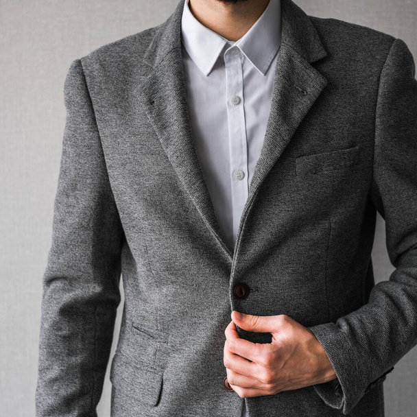 egy férfi klasszikus szürke dzsekiben és fehér ingben, világos háttérrel. üzletember öltönyben. mockup - Fotó, kép