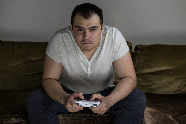 A man plays a video game console and is angry that he is losing. A disgruntled man loses in a video game. - Photo, image