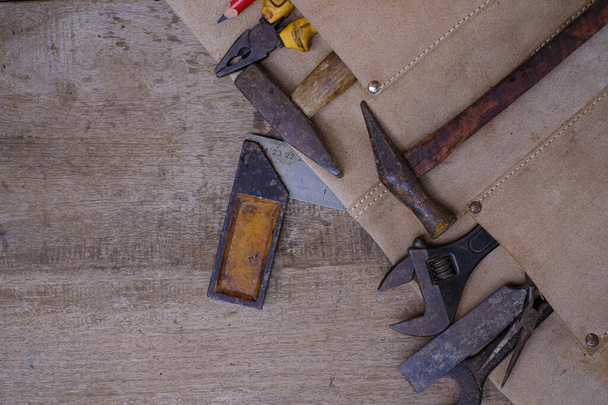 Collection d'outils à main de travail du bois en tablier de cuir sur établi rugueux en bois - Photo, image
