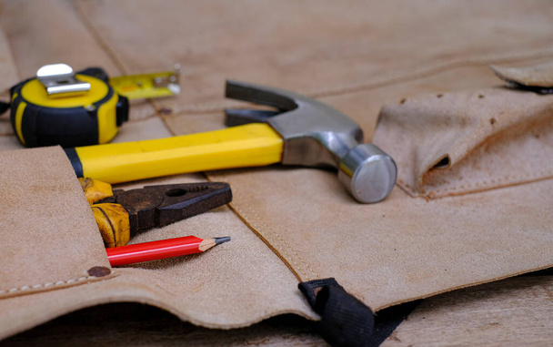 Colección de herramientas de mano antiguas de carpintería en delantal de cuero sobre una madera rugosa del banco de trabajo - Foto, Imagen