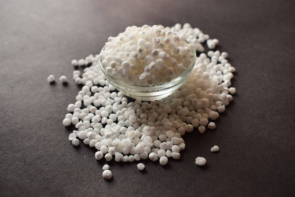 Perles ou boules de graines de sagou blanc dans un bol en verre transparent sur fond noir isolé - Photo, image