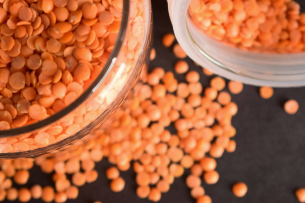 Top View Closeup Red Lentils in a Open Transparent Glass jar On isolated Black Background - Photo, Image
