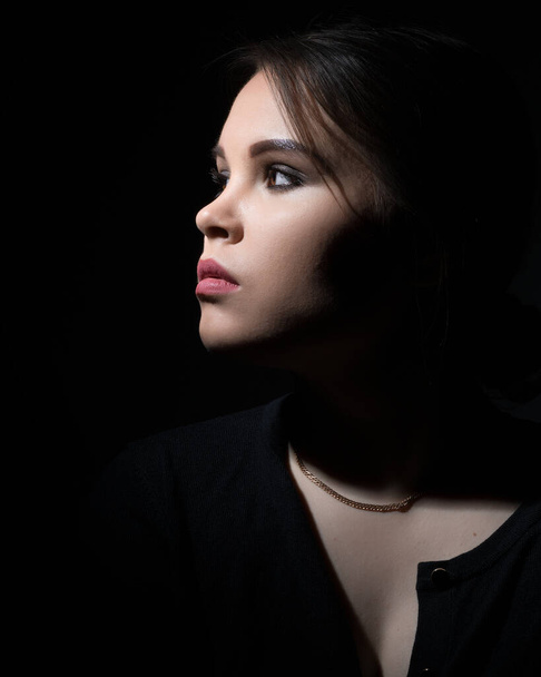 portrait of a girl sideways on a black background.copy space - Zdjęcie, obraz