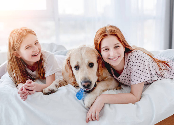 Girls with golden retriever dog in the bed - Photo, image