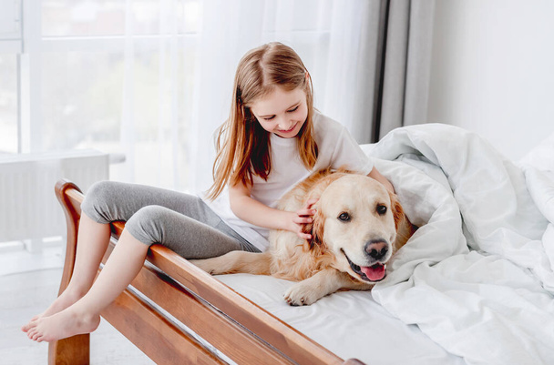 Girl with golden retriever dog in the bed - Foto, imagen