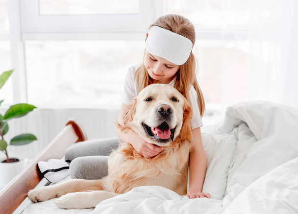 Girl with golden retriever dog in the bed - Фото, зображення
