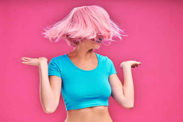 Pink Mood. Smiling trendy woman shaking pink hair isolated pink background - Фото, изображение