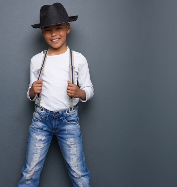 kleine jongen lachend met zwarte hoed en jarretelles  - Foto, afbeelding