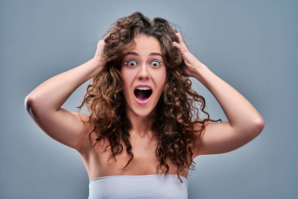 Hysterical woman expression with her hands on the head on a grey isolated background. - Foto, Imagem