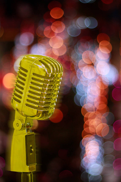 Smooth Focus, Το vintage χρυσό μικρόφωνο στο φόντο των πολύχρωμων bokeh φώτα της νυχτερινής λέσχης είναι ένα μικρόφωνο που είναι προετοιμασμένο για τραγουδιστές και ηθοποιούς να περνούν το χρόνο τους στη σκηνή. - Φωτογραφία, εικόνα