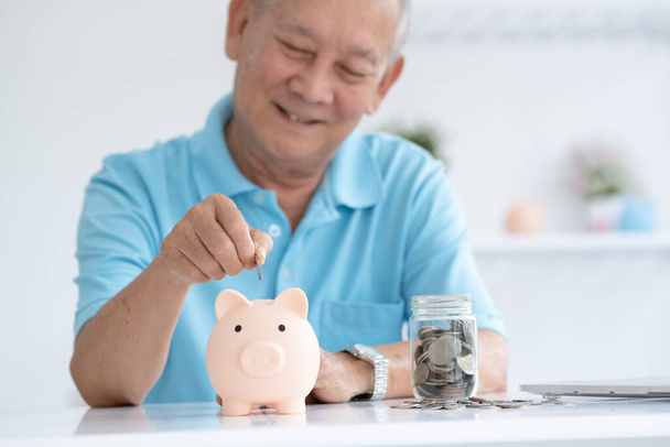 Anciano sonriendo poniendo una moneda dentro de alcancía como ahorro para la inversión y el ahorro de jubilación cepillado. - Foto, Imagen