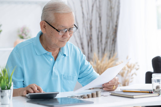 財務、貯蓄、年金保険、人々の概念-計算機や家庭でお金を数える法案を持つ高齢者。老人は家で税金を計算する - 写真・画像