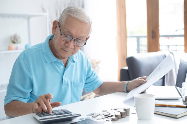 Finanse, oszczędności, ubezpieczenie emerytalne i koncepcja ludzi - senior man z kalkulatorem i rachunkami liczącymi pieniądze w domu. Starszy mężczyzna obliczający podatki w domu - Zdjęcie, obraz