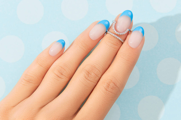 Όμορφες γυναίκες χέρια μοντέρνα σχεδιασμό καλοκαιρινών νυχιών σε μπλε φόντο - Φωτογραφία, εικόνα