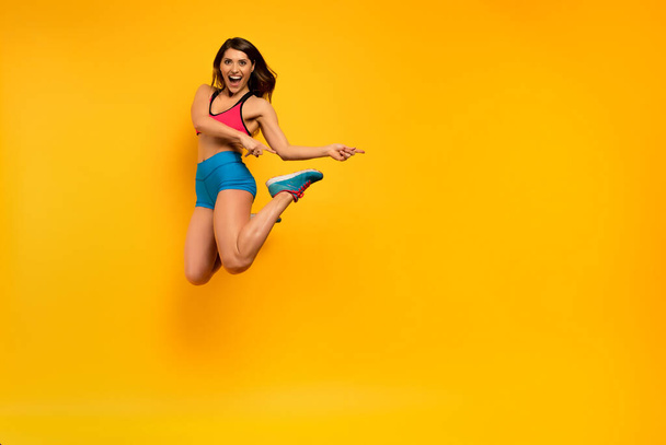 スポーツの女性は黄色の背景にジャンプします。幸せと喜びの表現. - 写真・画像