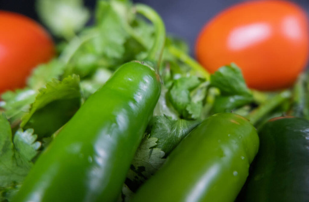 Close-up van chilipepers en tomaten boven koriander - Foto, afbeelding