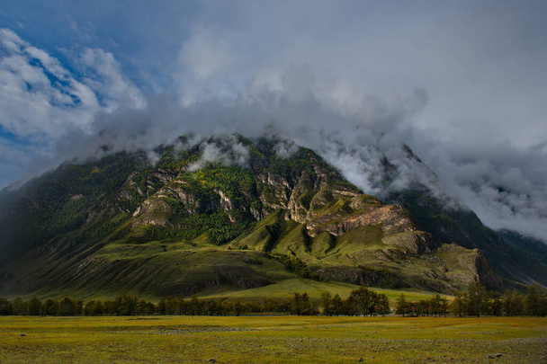 Rusland. Ten zuiden van West-Siberië, Mountain Altai. Ochtendmist op de bergtoppen in het dal van de Chulyshman Rivier bij de monding aan de zuidelijke oever van het Teletskoye Meer. - Foto, afbeelding