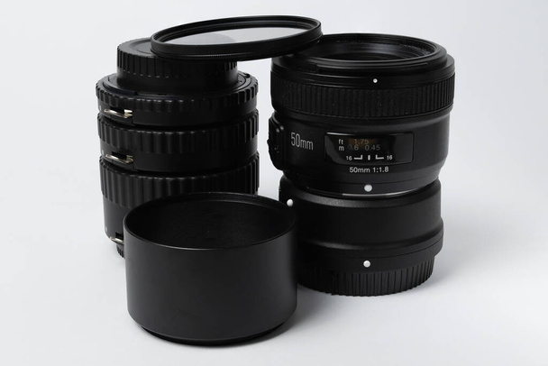 the lens with the macro rings and the lens hood are positioned vertically in the photo and are isolated - Photo, Image