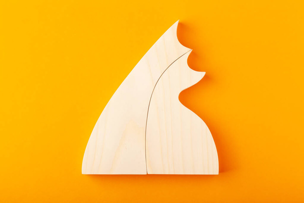 A figurine of hugging cats, carved from solid pine by a hand jigsaw. On a yellow background. - Фото, изображение
