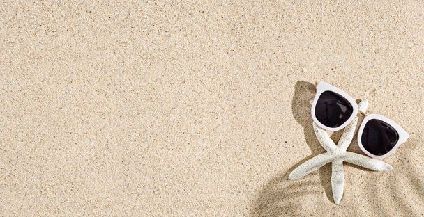 Морская звезда и белые солнцезащитные очки на природном песчаном фоне, пространство для копирования, вид сверху - Фото, изображение