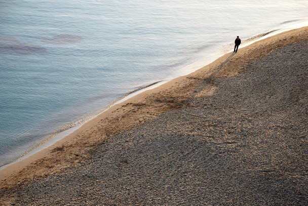 man walking alone in a beach on the seashore - Foto, Imagen