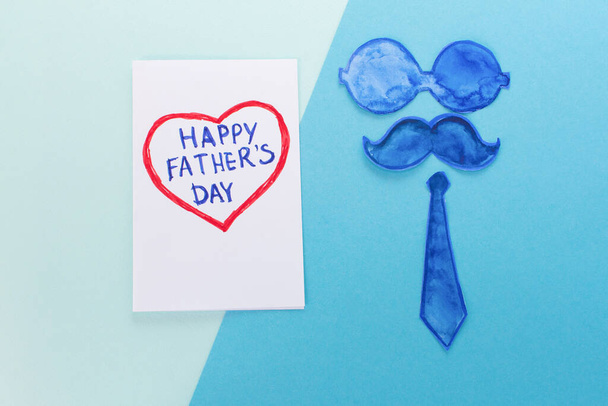 Father Day Concept. Funny mustache, glasses, tie and heart Card with the inscription: Happy Fathers Day on a minimal blue background. Copy space. - Foto, Imagem