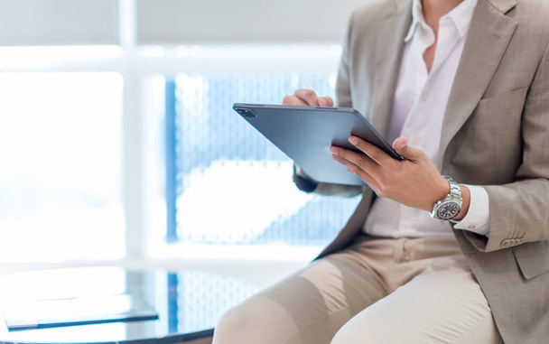 Businessman in brown suit hand holding tablet for writing and thinking in job at workspace in office. Male holding and using tablet computer. businessman with tablet  - Photo, image