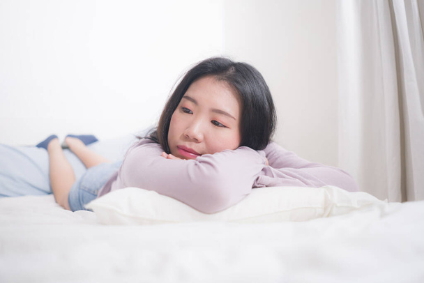 young Asian woman depressed - young beautiful and sad  Japanese girl on bed with pillow feeling unhappy and broken heart suffering depression problem at home bedroom - Photo, Image