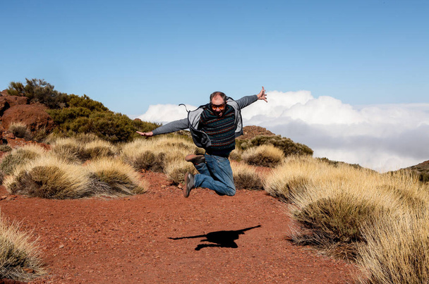 Turista feliz en pleno crecimiento en un salto. El viajero salta de alegría, haciendo un gesto de victoria. El hombre vino a descansar a Tenerife. - Foto, imagen