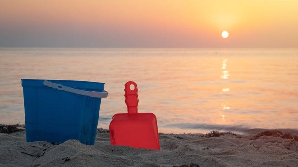 Children's beach toys - buckets, spade and shovel on sand on a sunny day - Fotó, kép