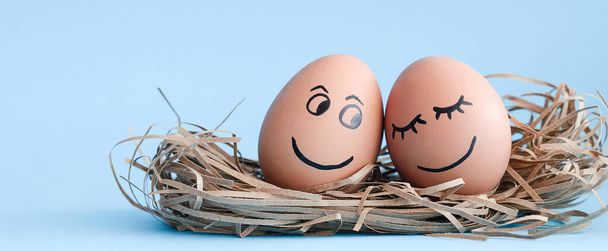 Felices huevos. Los huevos marrones dibujan una dulce sonrisa y una cara feliz. Fondo azul. El concepto de una vida feliz. - Foto, Imagen