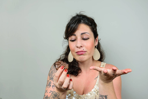 Wytatuowana kobieta z twarzą żalu za zjedzenie brazylijskiego ciasta miodowego. - Zdjęcie, obraz
