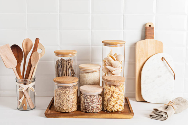 Assortment of cereals and pasta in glass jars and woden kitchen utensils. Zero waste idea - Foto, imagen