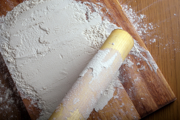 flour with a rolling pin on cutting board. - Photo, Image