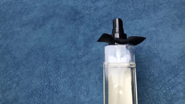 Vrouwelijke hand hagelslag parfum klikken op hen wijsvinger op een blauwe achtergrond. - Video