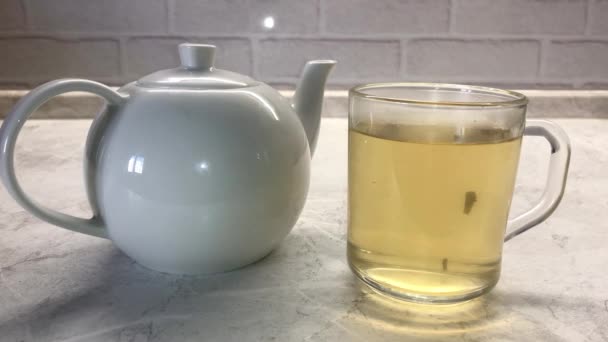 Жінка кидає два цукрові кубики в зелений чай у склянку прозорої чашки
. - Кадри, відео