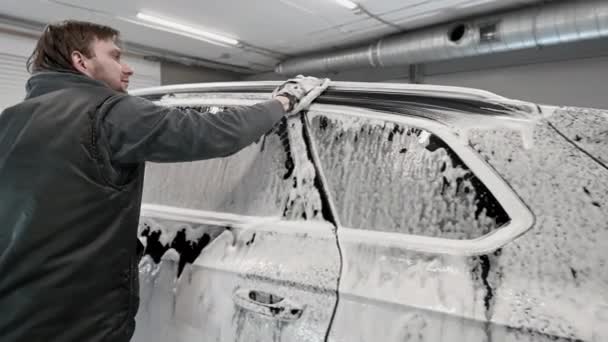 Auto detaillering - de man wast achtergrondverlichting van een auto met een hand bedekt met een speciale washandschoen, close-up. - Video