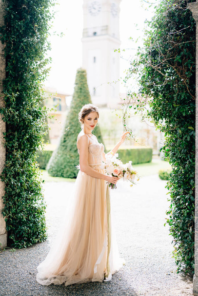 古い建物や庭園を背景に花の花束とドレスで笑顔の花嫁。イタリアのコモ湖 - 写真・画像