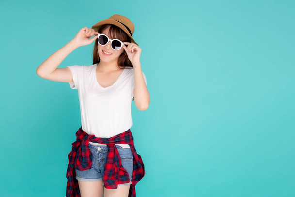 Красивый портрет молодой азиатской женщины носить шляпу и держа солнцезащитные очки улыбаясь уверенно наслаждаться путешествием летнее путешествие в отпуск изолированы на голубом фоне, туристическая Азия девушка весело с путешествием. - Фото, изображение