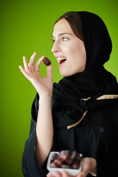 Young muslim girl wearing traditional muslim clothes holding dried dates. Arab girl representing iftar time, holy fasting month, Ramadan Kareem - Photo, Image