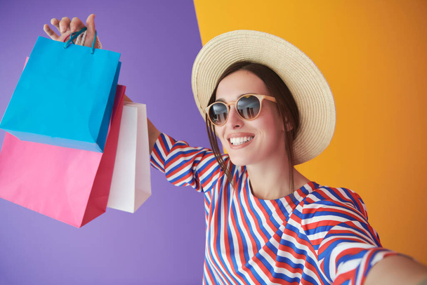 Young woman with shopping bags on colorful background. Happy girl posing with new purchases after a day of big sale. Black Friday concept - Foto, afbeelding